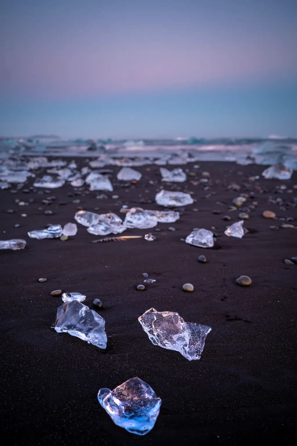 Frozen Serenity: Ice Fragments on a Black Sand Beach at Dusk