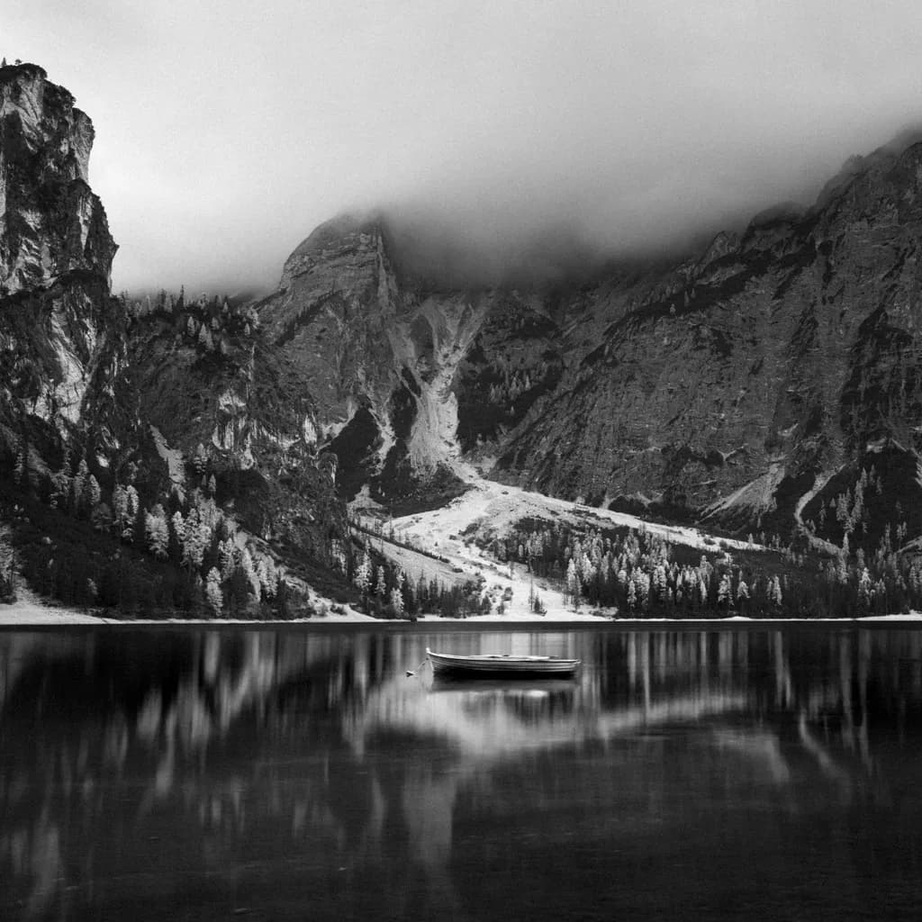 Whispers of Solitude: A Serene Boat on a Misty Lake Amidst Majestic Mountains