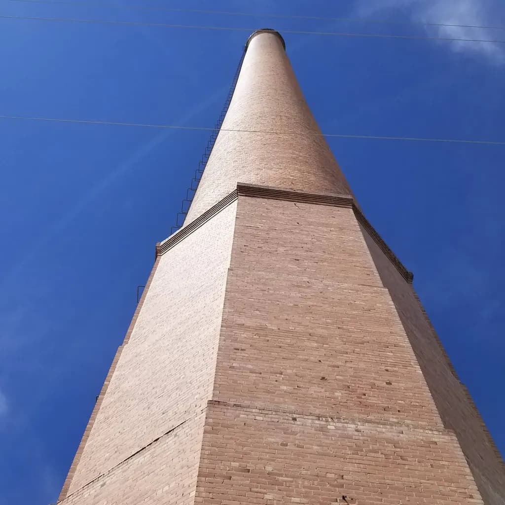 Towering Legacy: A Vertical Journey Through Industrial History Under a Vast Blue Sky