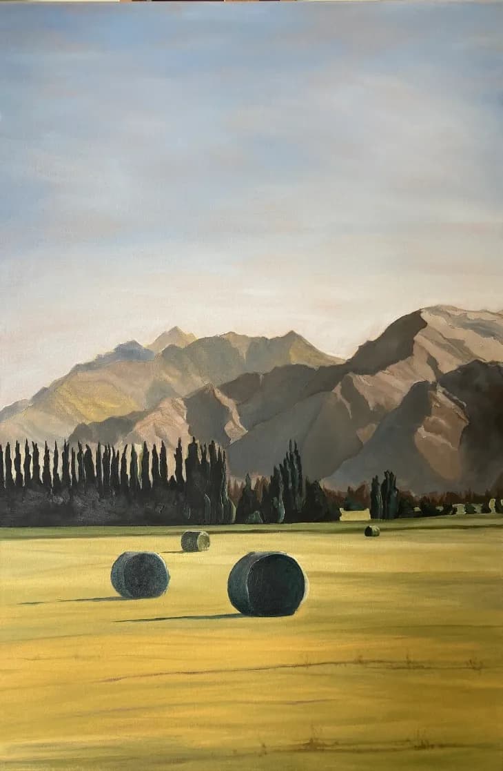 Serenity in the Fields: A Tranquil Landscape of Rolling Hay Bales and Majestic Mountains
