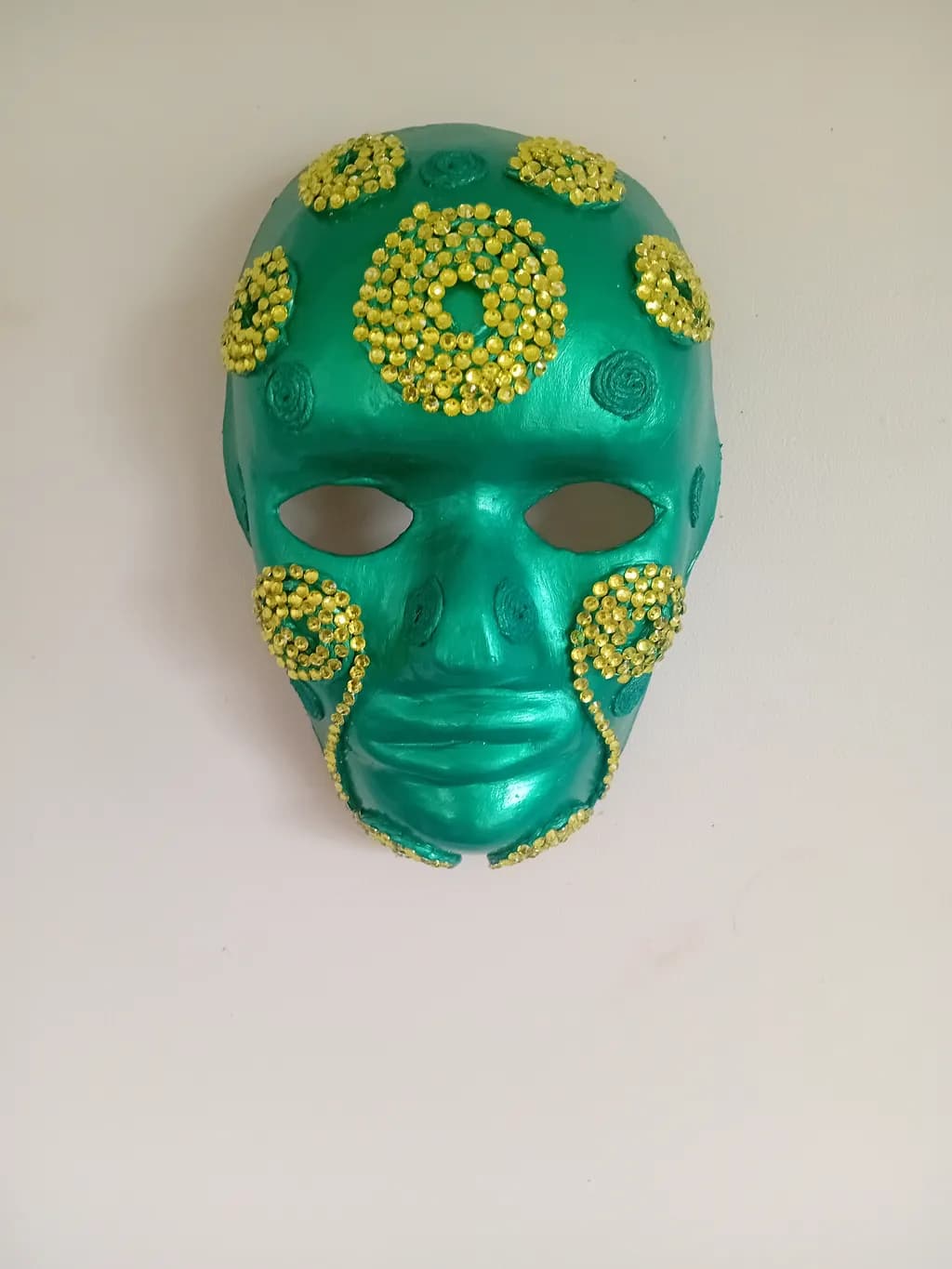 Vibrant Green Mask Adorned with Golden Spirals: A Unique Artistic Expression