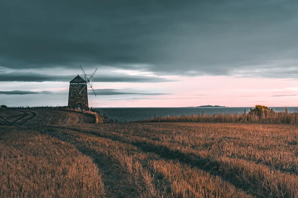 Whispers of the Wind: A Serene Evening by the Sea with a Rustic Windmill