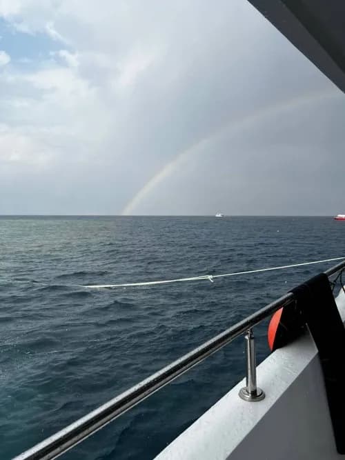 Serenity at Sea: A Rainbow's Embrace Over Tranquil Waters