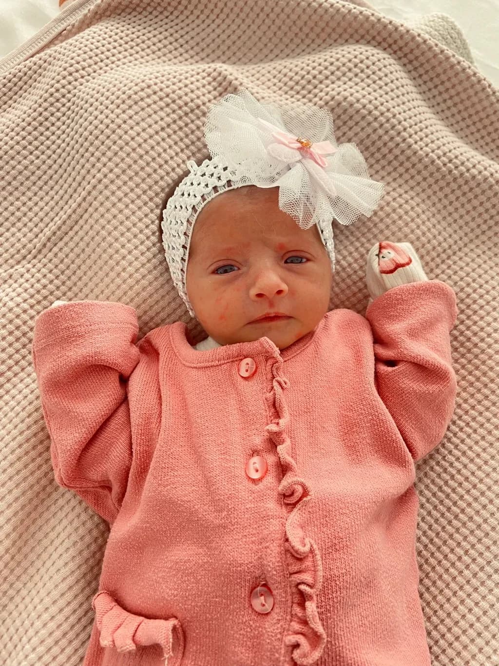 Whispers of Innocence: A Newborn's Serene Gaze in Soft Pink Elegance