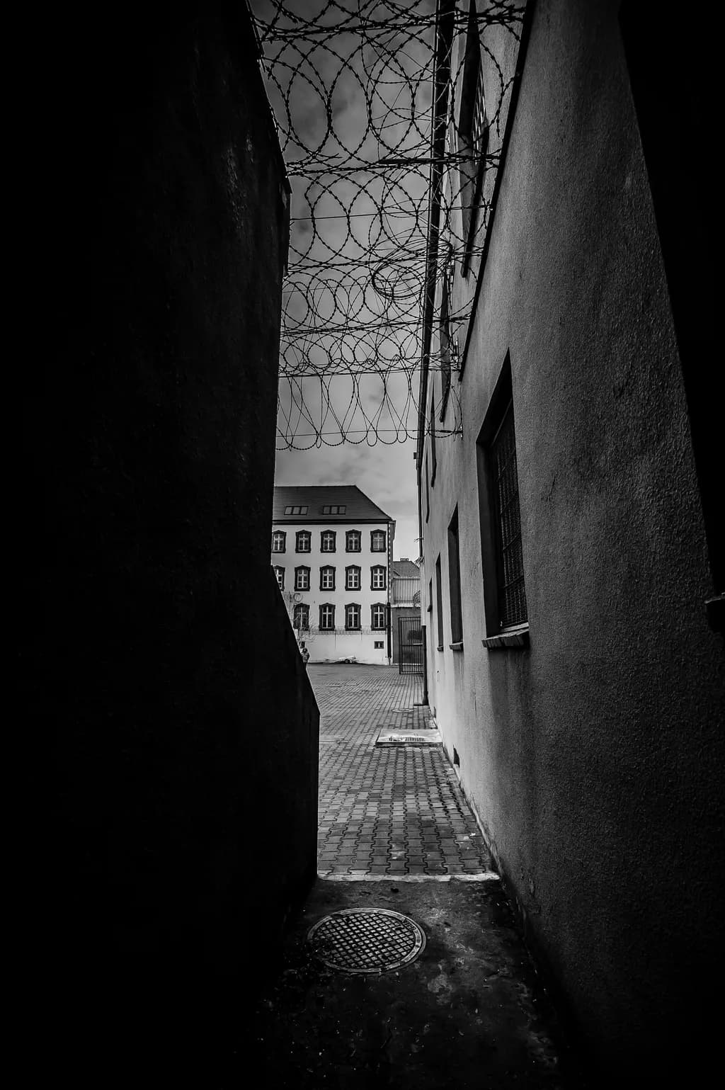 Shadows of Confinement: A Haunting Passage Through Barbed Wire and Stone
