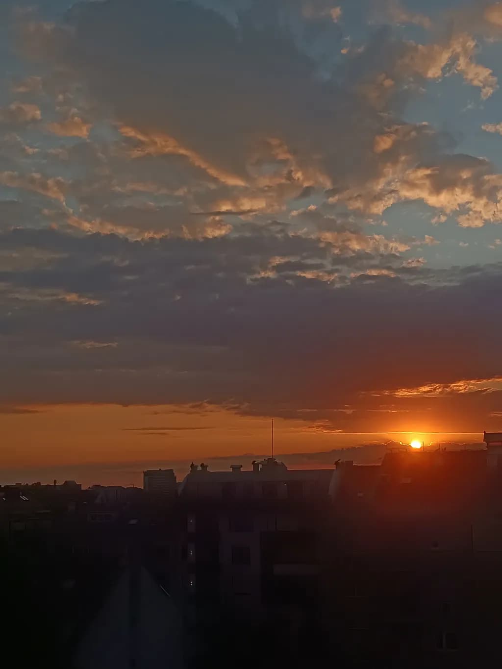 Serene Cityscape at Sunset: A Tranquil Evening Sky with Clouds and Warm Hues