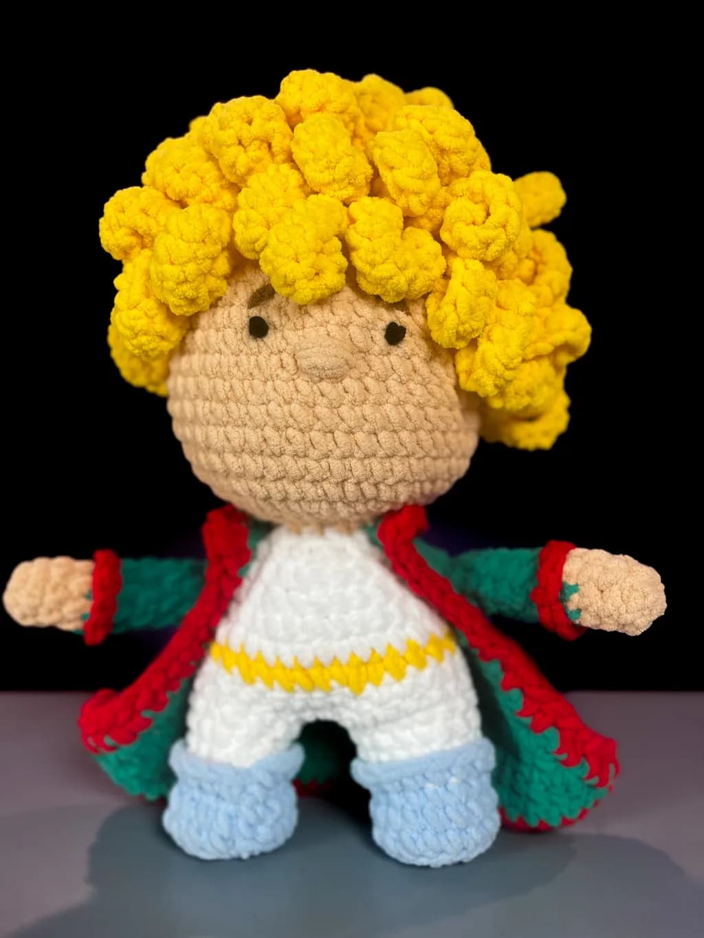 Whimsical Crochet Character with Golden Curls and Colorful Cape