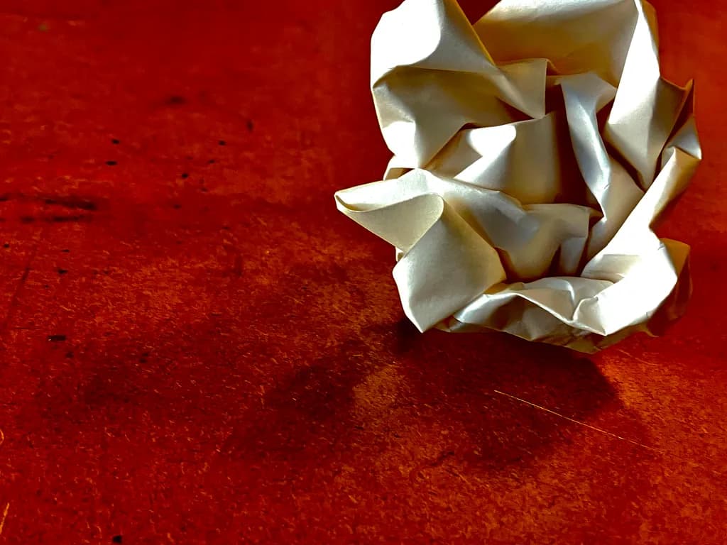 Crumpled Whispers: An Abstract Dance of Paper and Shadow on Red Canvas