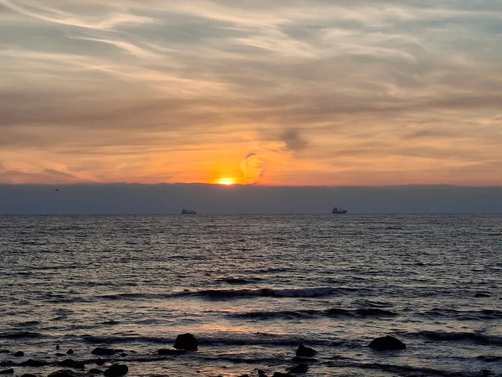 Serenity at Dusk: A Tranquil Sunset Over the Ocean with Silhouetted Ships