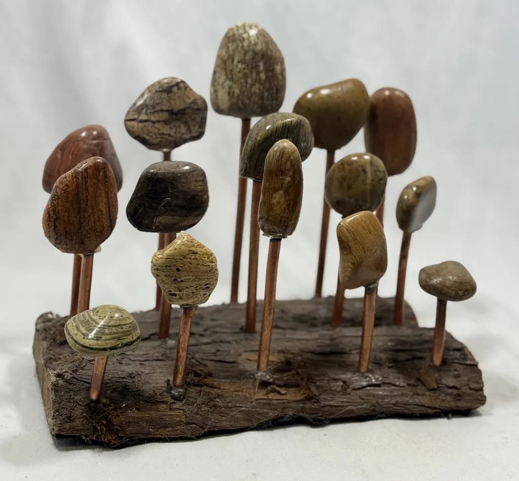 Sculptural Serenity: Polished Stones and Copper Rods Create a Tranquil Forest Display
