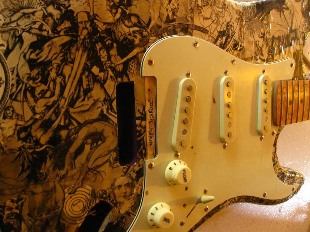 Guitar with photo collage cutouts of man's myths and popular religions