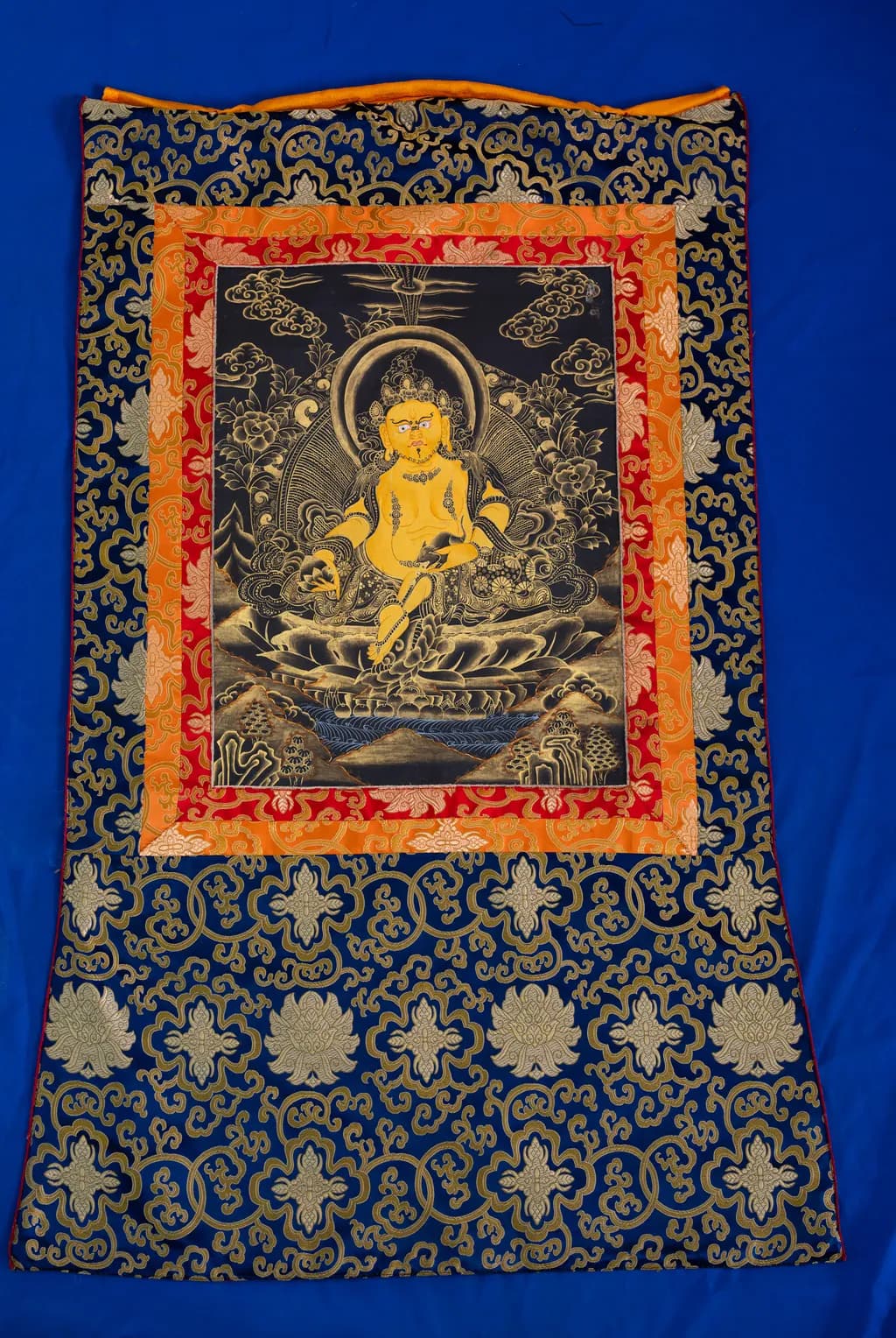 Yellow God of Wealth thangka painted with gold on a black background