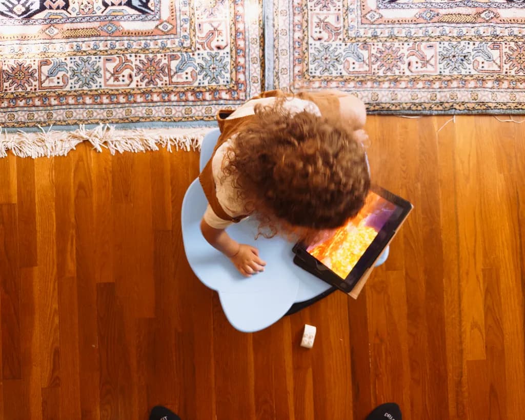 Child and Tablet on Wooden Floor