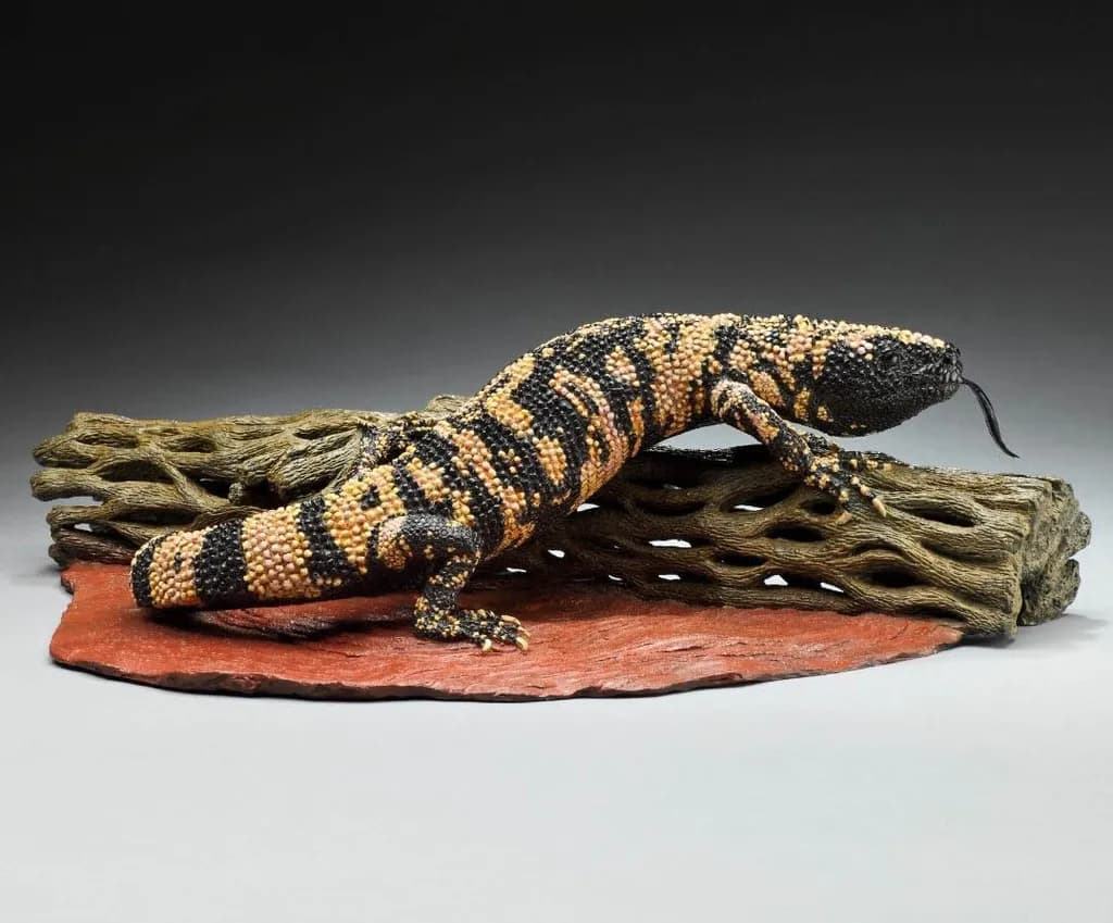 Vibrant Harmony: The Striking Gila Monster Sculpture on Natural Wood Base