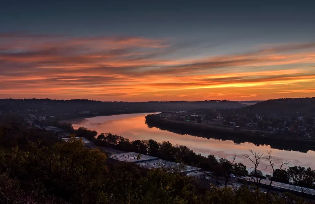 Serenity at Dusk: A Tranquil River Sunset Over Hillside Reflections
