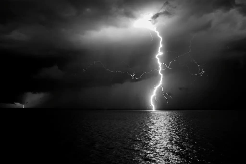 Electric Dance of Nature: A Striking Black and White Lightning Storm Over Water