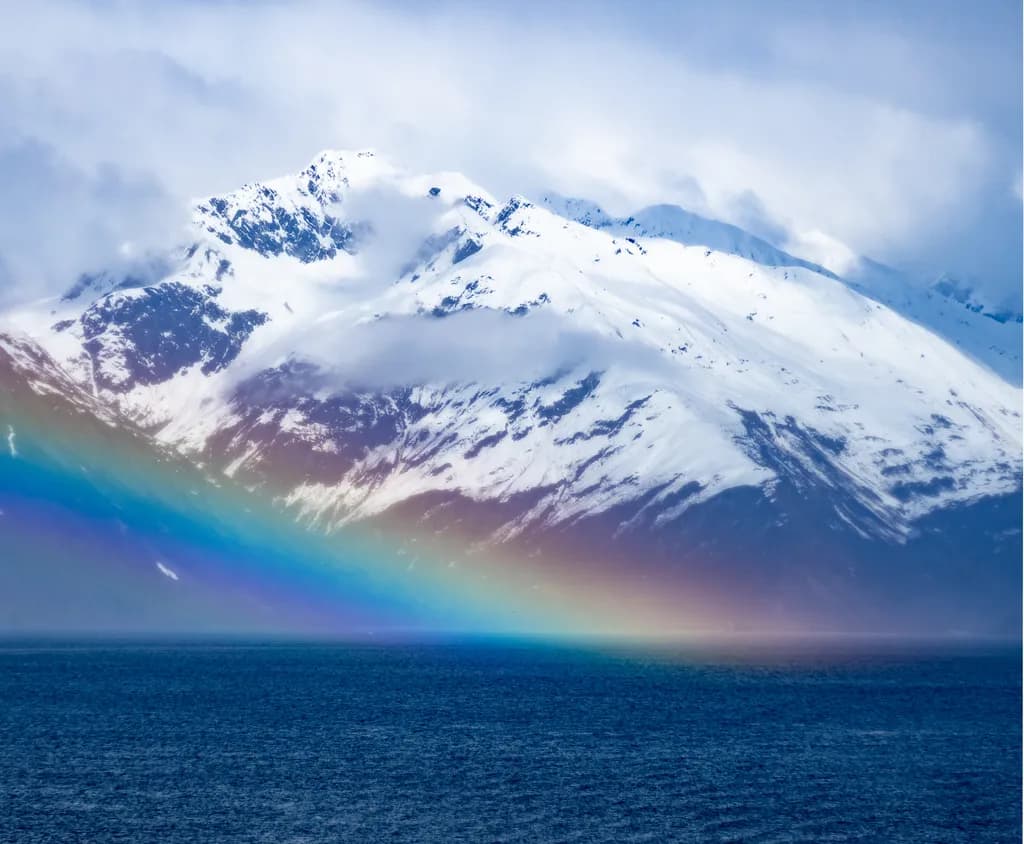 Majestic Harmony: A Rainbow's Embrace Over Snow-Capped Peaks and Serene Waters