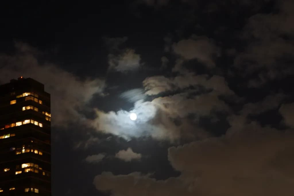 Moonlit Whispers: A Nighttime Dance of Clouds and City Lights