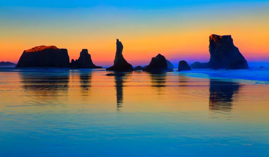 Serenity at Sunset: Reflections of Coastal Monoliths in Tranquil Waters