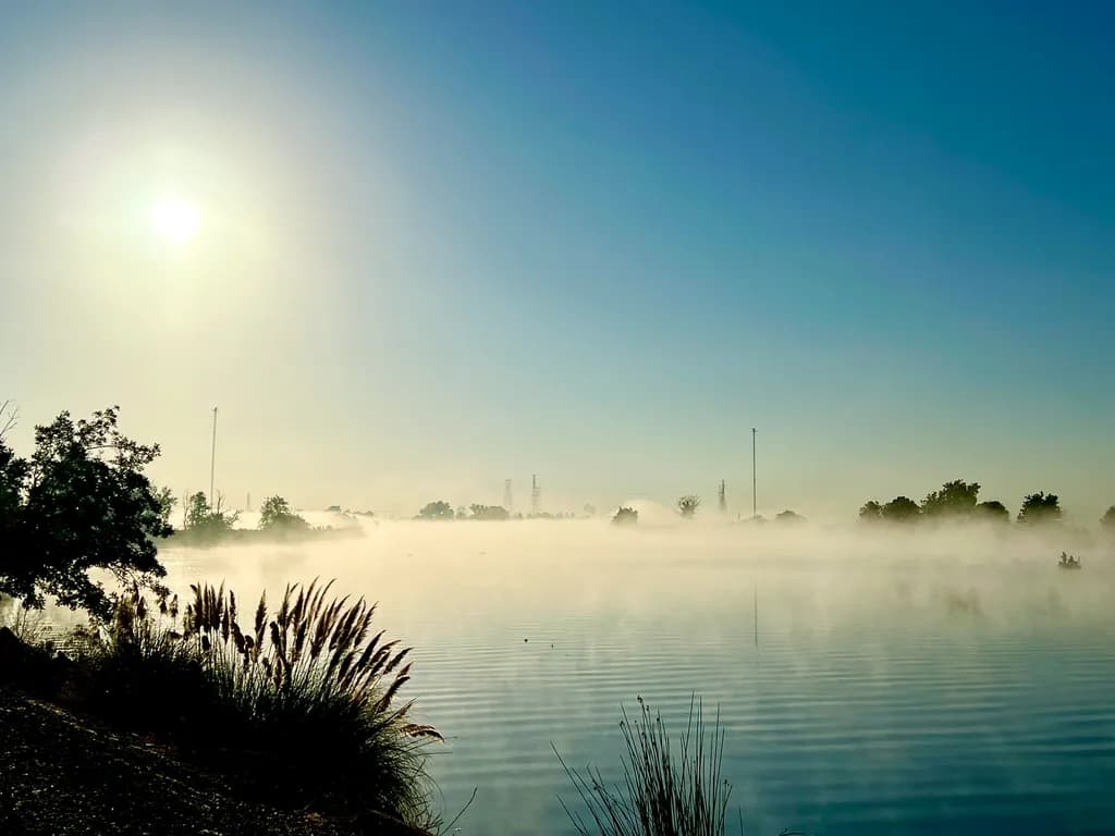Whispers of Dawn: A Serene Morning Mist Over Tranquil Waters