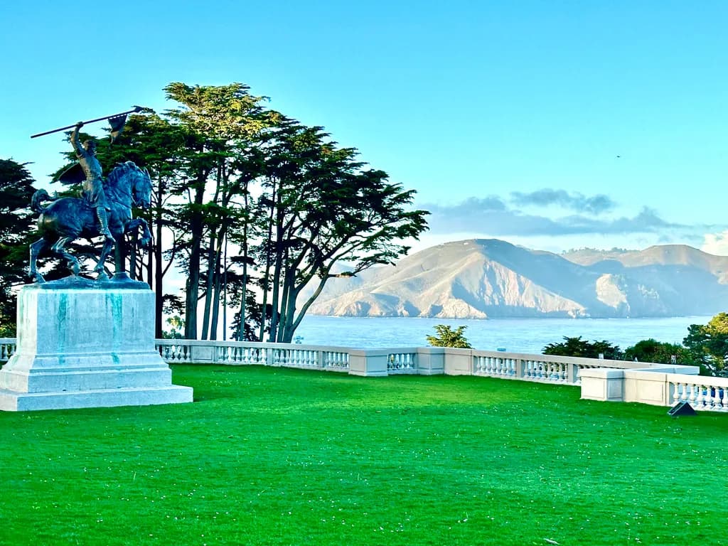 Majestic Sentinel: A Statue Overlooking the Serene Coastline and Lush Landscape