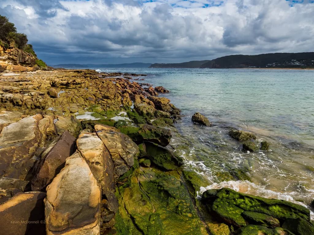 Serenity by the Shore: A Coastal Symphony of Rocks and Water Under Dramatic Skies