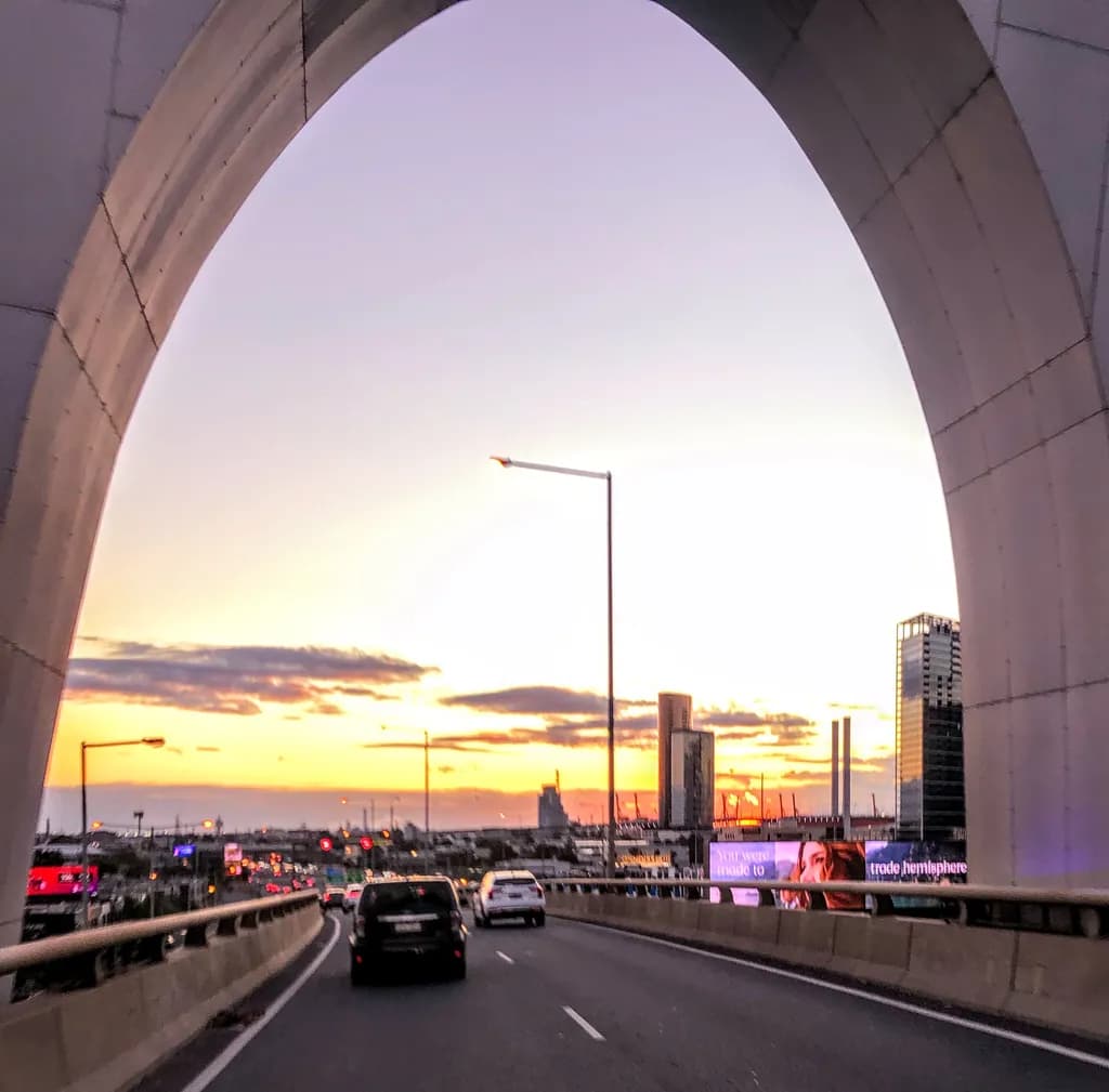 Urban Sunset Through the Arch: A Journey of Light and Motion