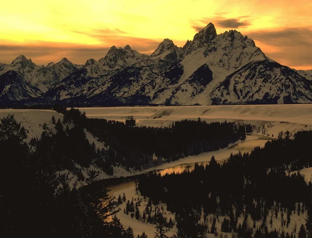 Serenity at Dusk: A Majestic Sunset Over Snow-Capped Mountains and a Tranquil River