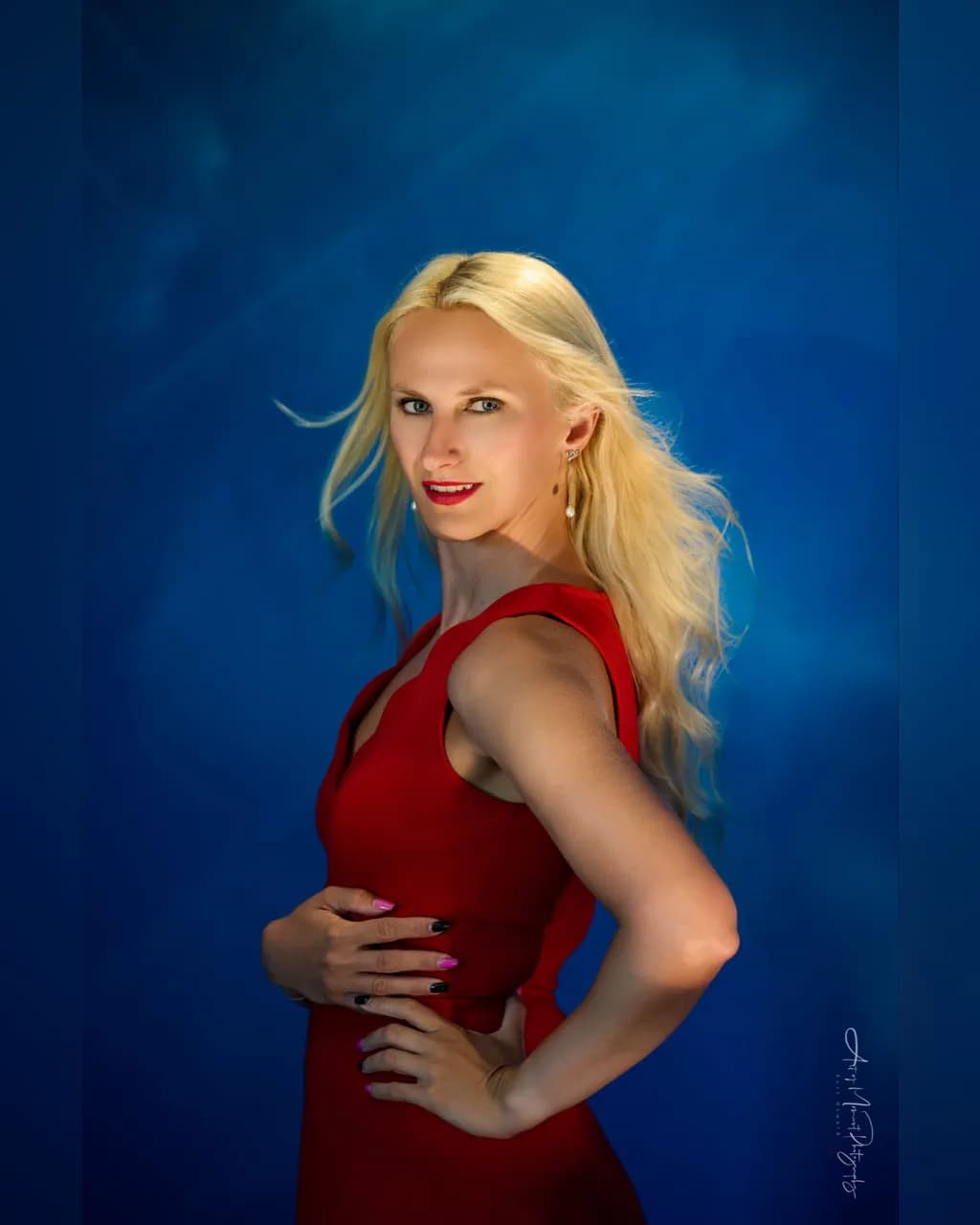 Radiant Elegance: A Striking Portrait of Grace in Red Against a Serene Blue Background