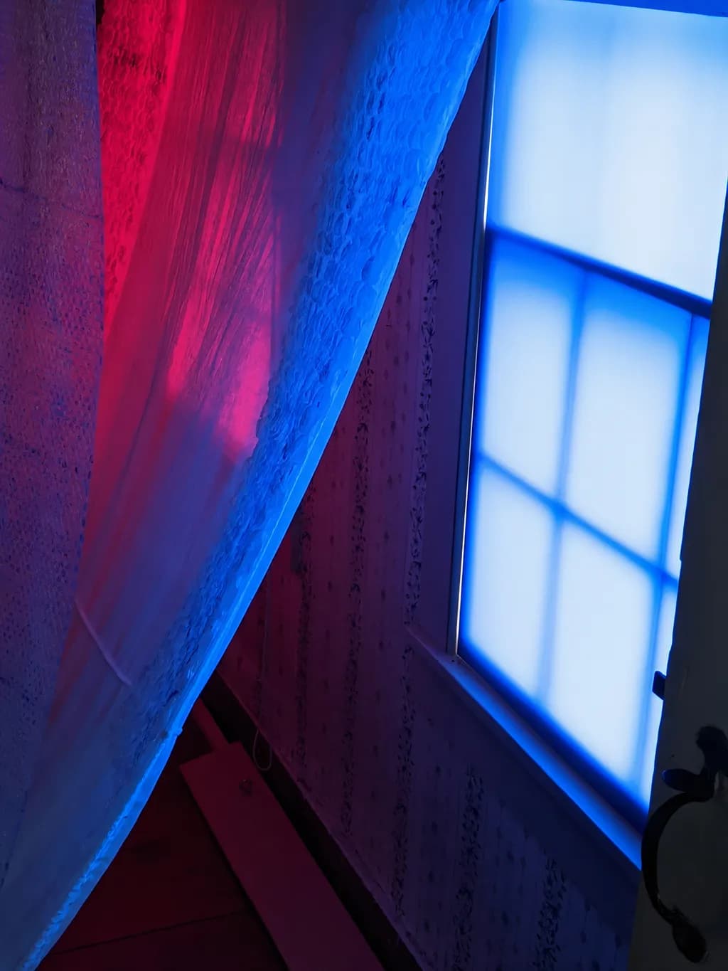 Whispers of Light: A Dance of Red and Blue Through the Window Veil