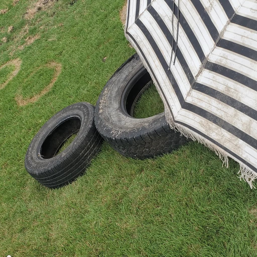Tires and Striped Umbrella on Grass