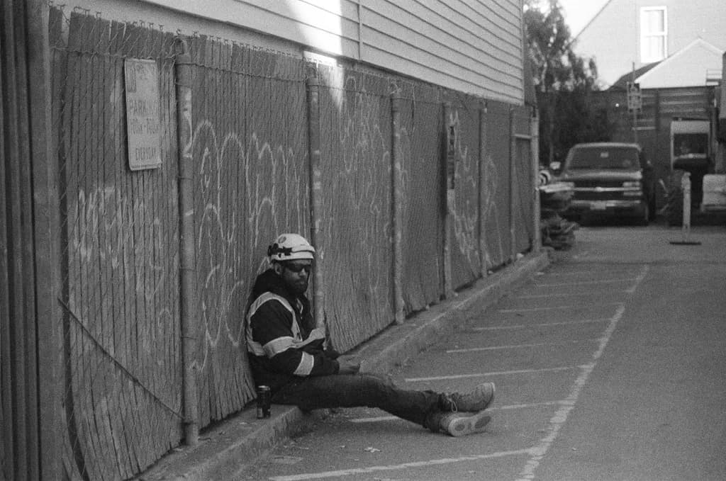 Worker Resting by Fence