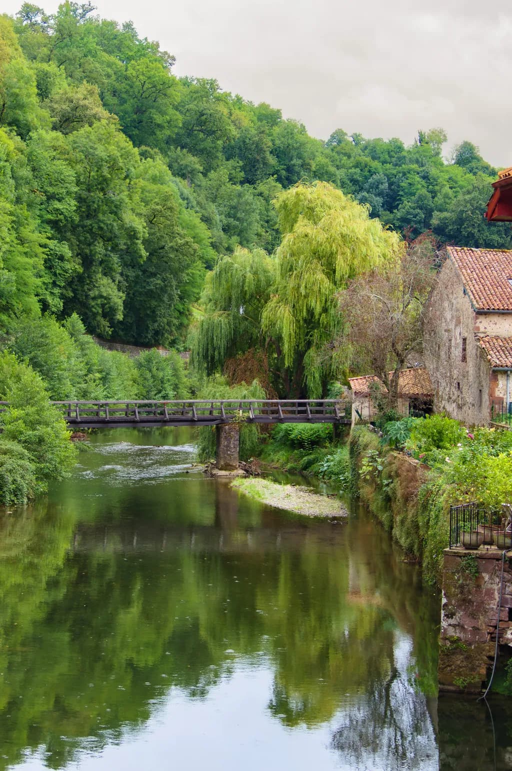 Whispers of Tranquility: A Serene River Scene with a Rustic Bridge and Lush Greenery
